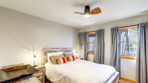 A bedroom with a bed, nightstands, a ceiling fan, and windows with curtains. - Deer River Retreat: Cabin Feel w/ Modern Touches (Sparta)