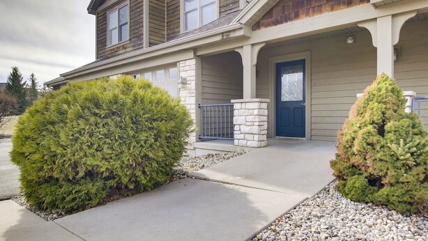 A two-story house with a porch, stone pillars, and a blue door. - 'rise and Shine in Door County!' Egg Harbor Haven (Egg Harbor)