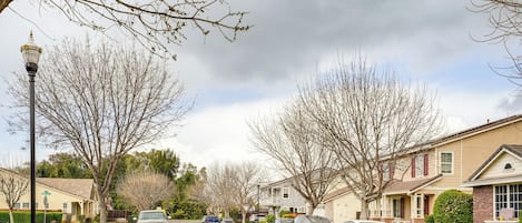 A residential street with houses, parked cars, and a street lamp.