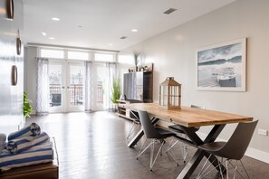 Un espace repas moderne avec une table en bois, des chaises noires et un téléviseur.