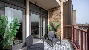Ein Balkon mit zwei Stühlen, einem gemusterten Boden und Blumentöpfen.