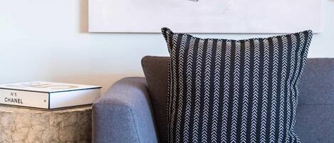 A modern living room with a grey sofa, a patterned throw pillow, and a large abstract painting on the wall.