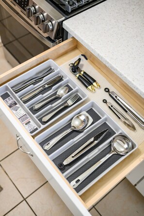 A drawer with neatly organized kitchen utensils including spoons, forks, and knives.
