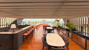 Een modern buitengebied met een bar, een houten vloer, zitplaatsen en uitzicht op zee.