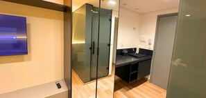 Un baño moderno con cabina de ducha de vidrio, un lavamanos con encimera negra y un inodoro.