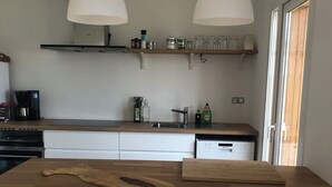 Een moderne keuken met twee witte stoelen, een houten kookeiland en hanglampen.