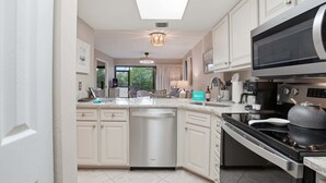 Une cuisine moderne avec des meubles blancs, un lave-vaisselle, une cuisinière et un four à micro-ondes.