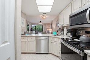 Una cocina moderna con armarios blancos, lavavajillas, estufa y microondas.
