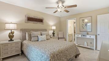 A bedroom with a bed, nightstands, a dresser, a ceiling fan, and a door.