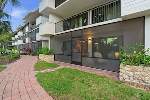 A modern building with a curved brick pathway leading to a gated entrance. - G-144 - First Floor - End Unit With Lake Views! (Naples)