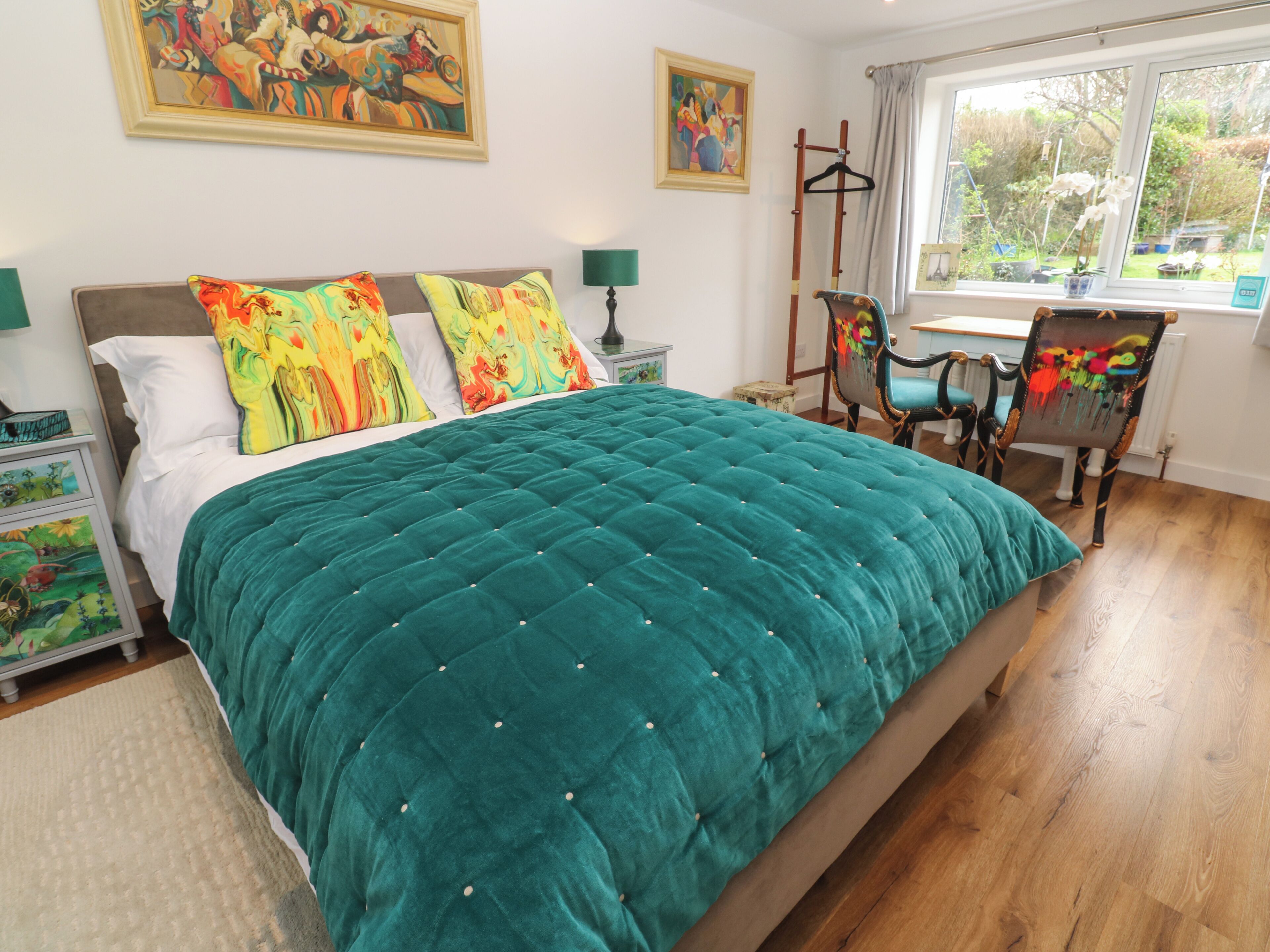 Un dormitorio con una cama grande, almohadas coloridas, un escritorio y una silla.