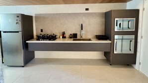 A modern kitchen with a wooden ceiling, stainless steel appliances, and a large island with a sink. - Urban - Ed. Luciene (Recife)