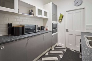 A compact kitchen with a microwave, toaster, and oven. - Host & Stay | Queen Street Apartment (Amble)