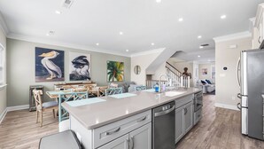 Une cuisine moderne dotée d’un grand îlot central, d’appareils électroménagers intégrés et d’œuvres d’art accrochées aux murs.