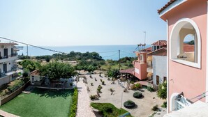 Un quartier résidentiel offrant une vue sur la mer, avec un terrain de jeux et une cour dallée agrémentée de plantes en pot.