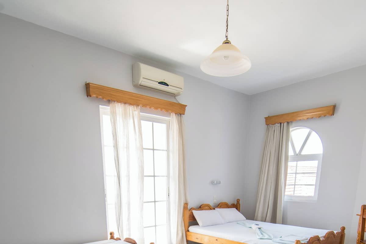A room with three wooden beds, a ceiling fan, and an air conditioning unit.
