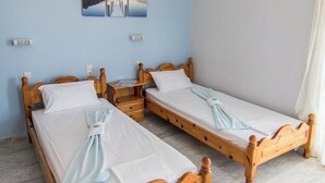 Une pièce avec deux lits en bois, un luminaire au plafond et un tableau accroché au mur.