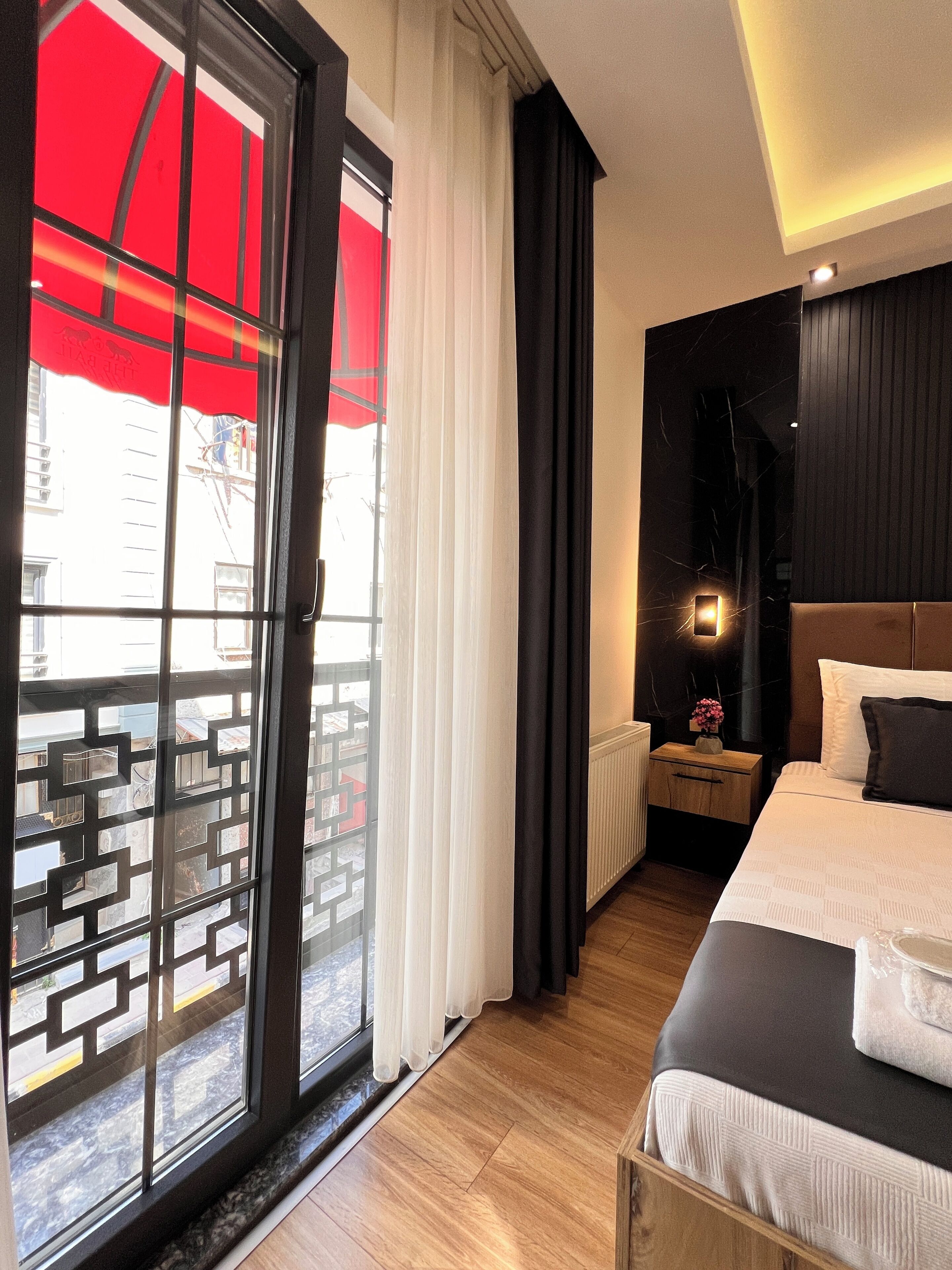 A hotel room with a bed, a nightstand, a lamp, and a view through a sliding glass door.