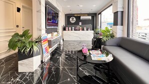En moderne lobby med reception, fladskærms-tv og siddeområde.