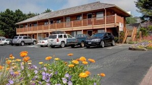 A two-story lodge with a wooden exterior and a balcony on the upper floor. There are several cars parked in front.