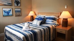 Une chambre d’hôtel comprenant un lit, deux lampes de chevet et quatre tableaux accrochés au mur.
