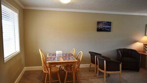 Un coin repas avec une table et des chaises, un tableau au mur et une lampe sur une table d’appoint.