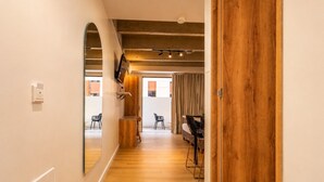A hallway with wooden flooring, a wooden door, and a mirrored wall. - Loft in Laureles with kitchenette, AC & workspace (Medellín)
