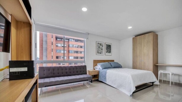 Une chambre à coucher moderne avec un lit, un banc, une armoire et un bureau.