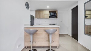 Une cuisine moderne dotée d’un îlot central, de meubles en bois, d’un four à micro-ondes et d’un évier.
