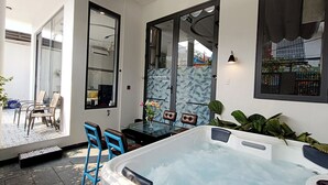 A spa area with a hot tub, blue chairs, and a glass table. - Aroma My Khe Beach (Da Nang)