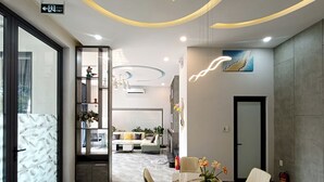 A modern hotel lobby with a marble floor, a central dining table with chairs, a sofa area, and a reception desk. - Aroma My Khe Beach (Da Nang)