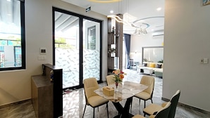 A modern dining area with a marble table, beige chairs, and a vase of flowers. - Aroma My Khe Beach (Da Nang)