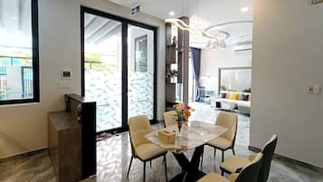 A modern dining area with a marble table, beige chairs, and a vase of flowers.