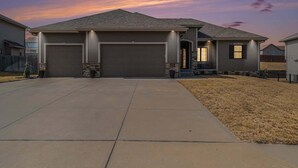 A residential house with a garage, a driveway, and a well-maintained lawn. - Spacious Retreat in West Omaha 2 King 3 Queen Beds (Omaha)