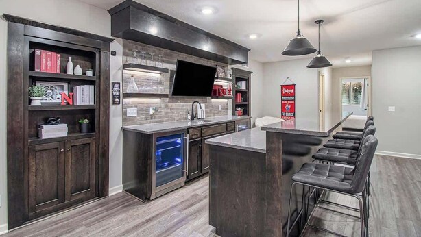 A modern kitchen with dark wood cabinetry, a built-in oven, and a bar area with stools. - Spacious Retreat in West Omaha 2 King 3 Queen Beds (Omaha)