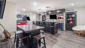 A modern kitchen with a central island, bar stools, and a dining table. - Spacious Retreat in West Omaha 2 King 3 Queen Beds (Omaha)