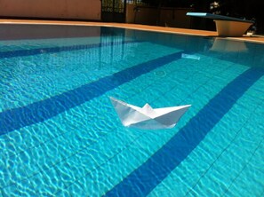 Una piscina con una barchetta di carta che galleggia sull'acqua.