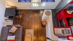 A compact living space with a sofa, a dining table, a kitchen area with red cabinets, and a ceiling fan. - Magnificient Duplex in Old Antibes ! (Antibes)