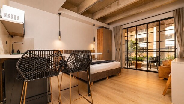 A modern room with a bed, a desk, and two chairs. - Monthly Studio with kitchenette-AC-private balcony (Medellín)