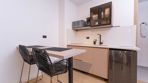 A compact kitchen with a dining table and chairs, a built-in oven, and a microwave above the counter.
