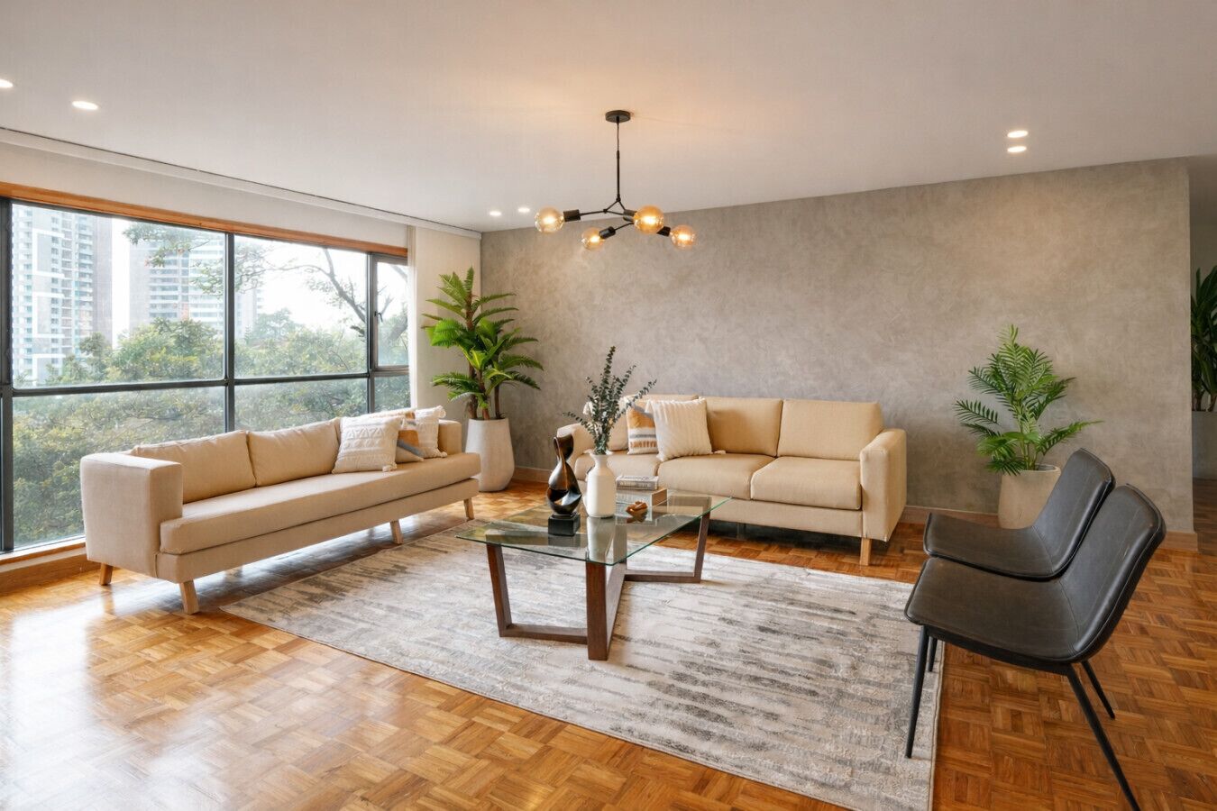 A spacious living room with a large window, two sofas, a glass coffee table, and a modern chandelier.