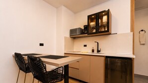 A compact kitchen with a dining table, chairs, a dishwasher, and a built-in cabinet with dishes. - Loft in Laureles - AC fast WiFi & private balcony (Medellín)