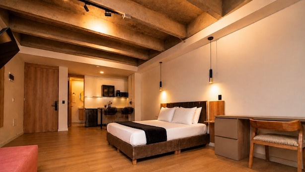 Une chambre comprenant un lit, un bureau, une chaise et un coin cuisine.
