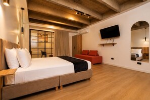 A modern hotel room with a large bed, a red sofa, a TV, and a mirror. - Loft in Laureles with a kitchenette, air conditioning, and a workspace (Medellín)