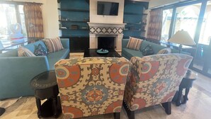 Ein Wohnzimmer mit zwei Sofas, einem Kamin und einem Fernseher.