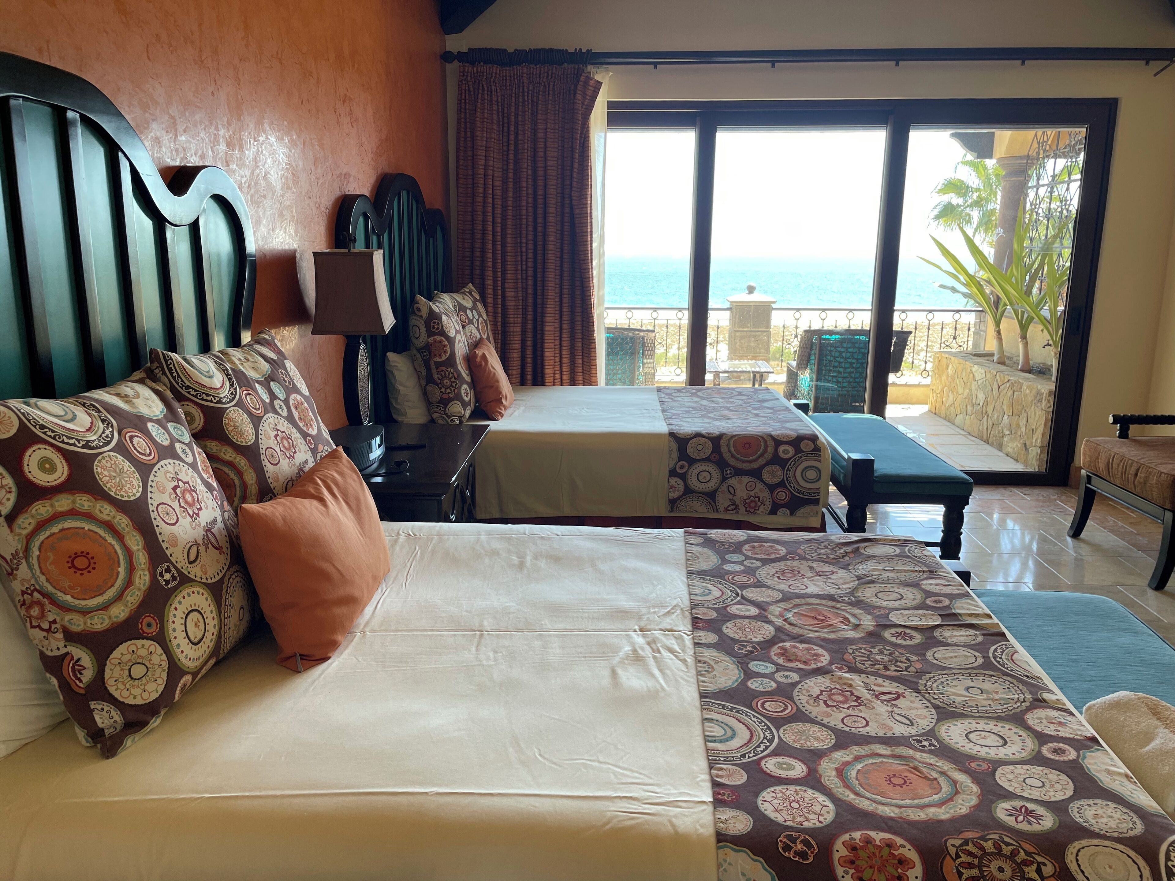 Ein Hotelzimmer mit zwei Betten, einem Tisch und Blick auf den Ozean.
