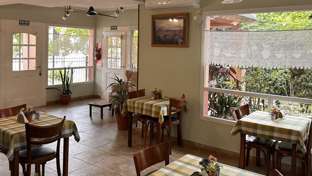 Un restaurant doté de nombreuses tables et chaises, de ventilateurs de plafond et de plantes en pot.