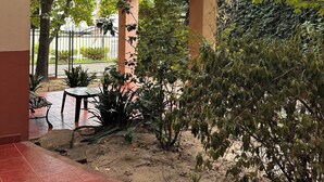 Un espace extérieur abrité, doté d’un sol carrelé, d’un banc en bois et de plantes en pot.