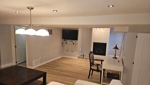 Ein Wohnzimmer mit einer Couch, einem Couchtisch, einem Fernseher, einem Kamin und einem Essbereich mit Tisch und Stühlen.