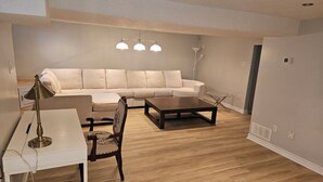 Ein Wohnzimmer mit einer Couch, zwei Couchtischen, einer Lampe und einem Sessel.